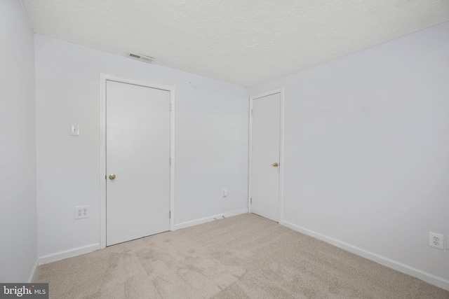 empty room with light carpet and a textured ceiling