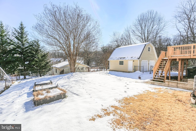 snowy yard featuring a wooden deck and an outdoor structure