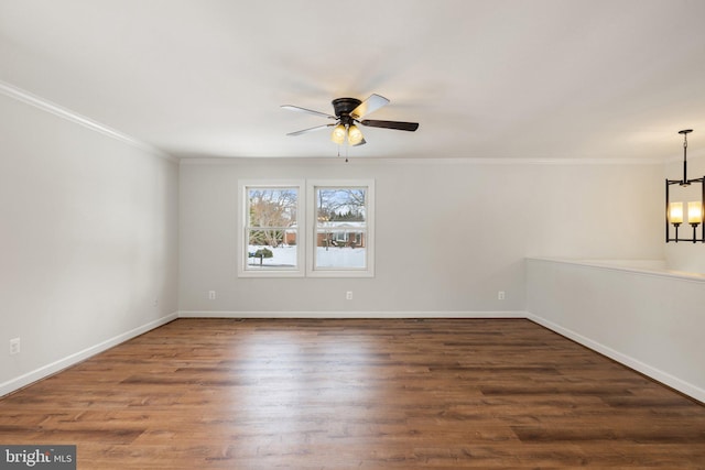 empty room featuring dark wood-type flooring, ceiling fan with notable chandelier, and ornamental molding