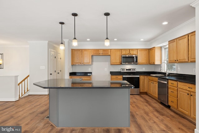 kitchen with sink, a kitchen island, hanging light fixtures, and appliances with stainless steel finishes