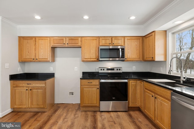 kitchen with hardwood / wood-style floors, sink, dark stone countertops, ornamental molding, and stainless steel appliances