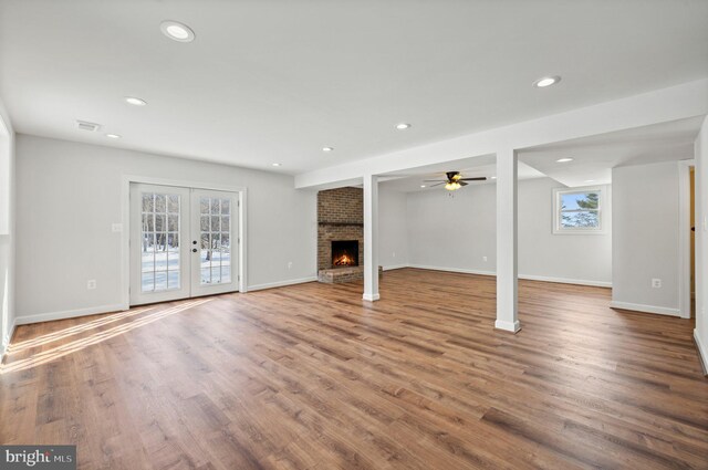 basement with a fireplace, ceiling fan, french doors, and hardwood / wood-style flooring