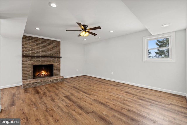 unfurnished living room featuring a fireplace, wood-type flooring, ceiling fan, and crown molding