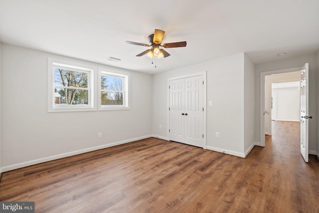 unfurnished bedroom featuring hardwood / wood-style floors, ceiling fan, and a closet