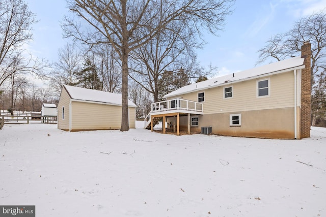 snow covered property featuring an outbuilding, a deck, and central air condition unit