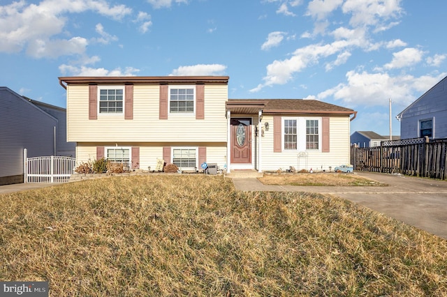 tri-level home with fence and a front yard