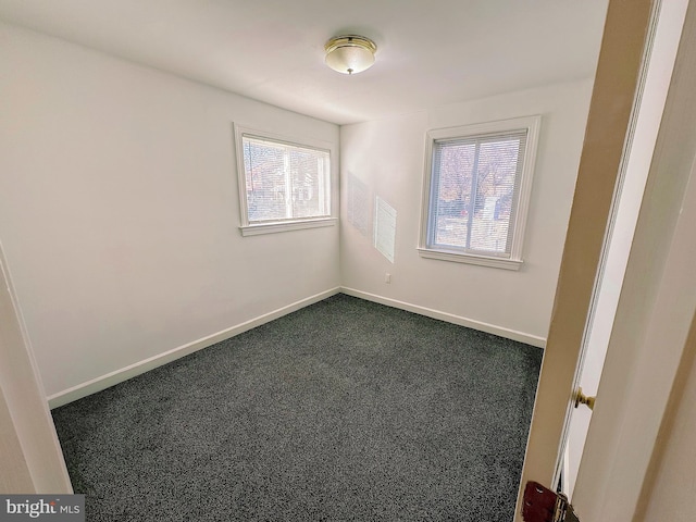 spare room featuring dark carpet