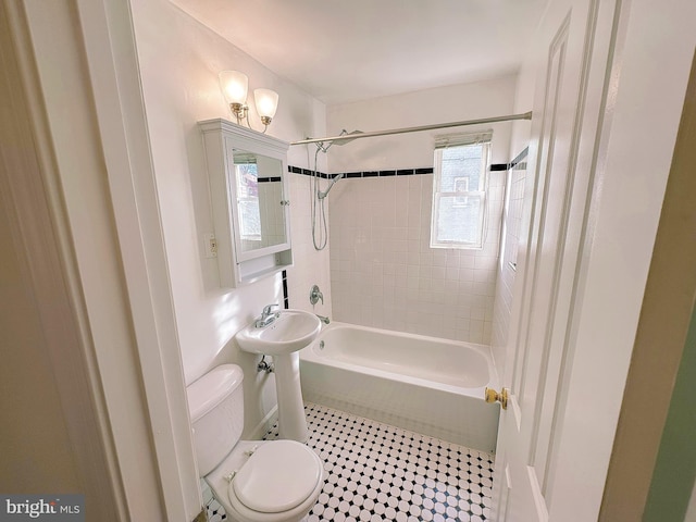 full bathroom featuring sink, toilet, a healthy amount of sunlight, and tiled shower / bath