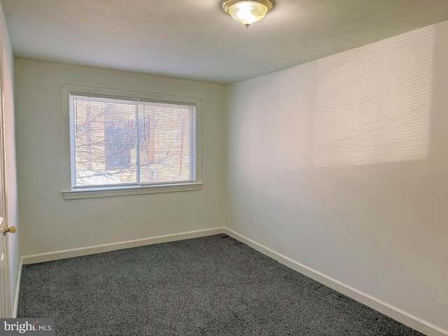 spare room featuring dark colored carpet