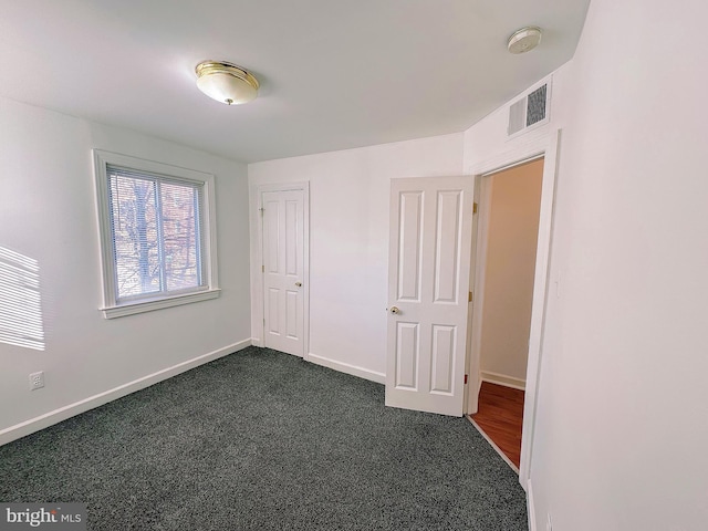 unfurnished bedroom featuring a closet and dark colored carpet