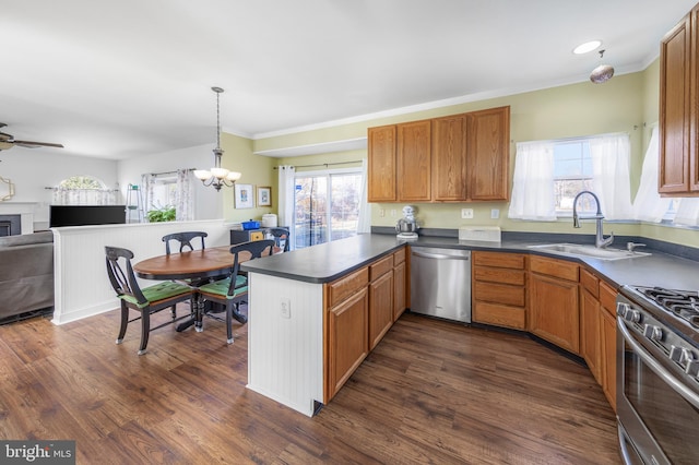 kitchen featuring kitchen peninsula, stainless steel appliances, dark wood-type flooring, sink, and hanging light fixtures