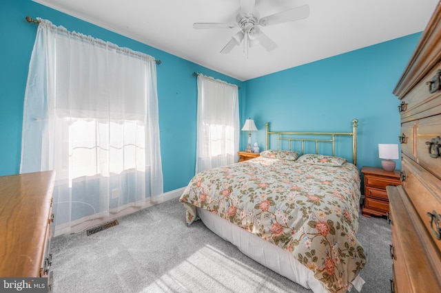 bedroom with ceiling fan, light carpet, and multiple windows