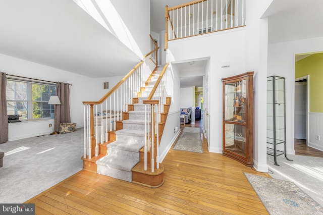 stairs featuring hardwood / wood-style flooring and a high ceiling