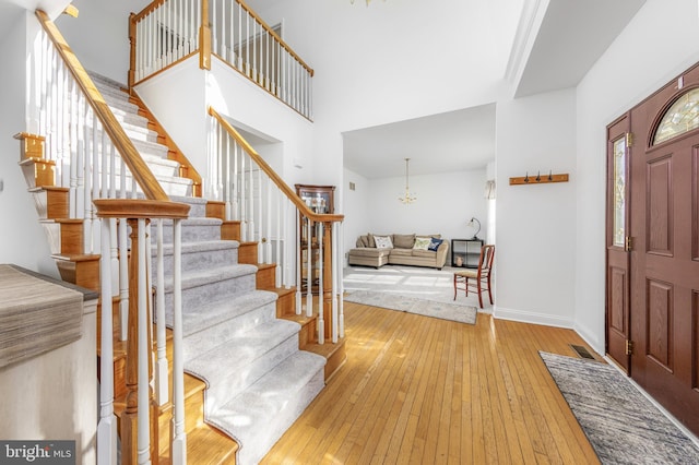 entrance foyer with an inviting chandelier, a towering ceiling, and light hardwood / wood-style flooring