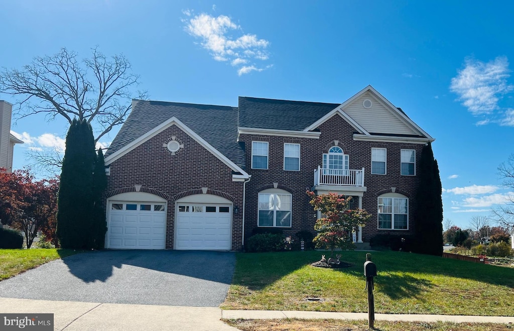 front of property with a balcony, a front yard, and a garage