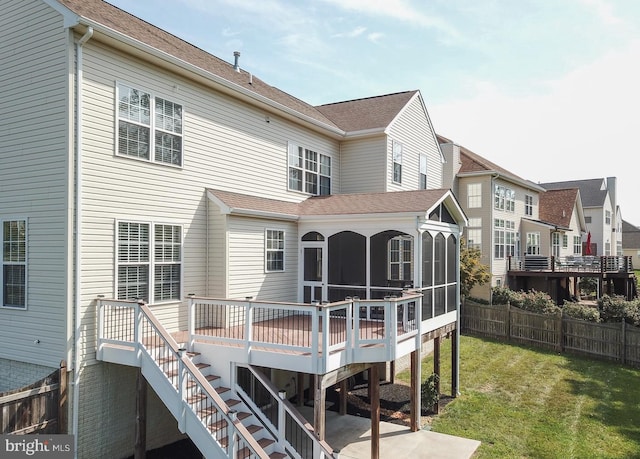 rear view of house featuring a sunroom, a yard, and a deck