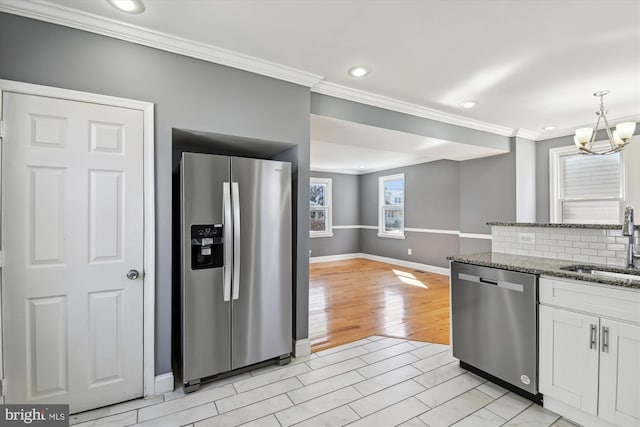 kitchen with tasteful backsplash, white cabinets, dark stone counters, appliances with stainless steel finishes, and a sink