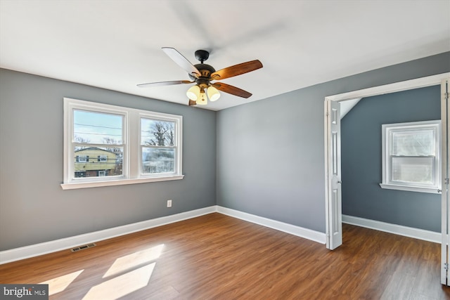 unfurnished room with wood finished floors, visible vents, and baseboards