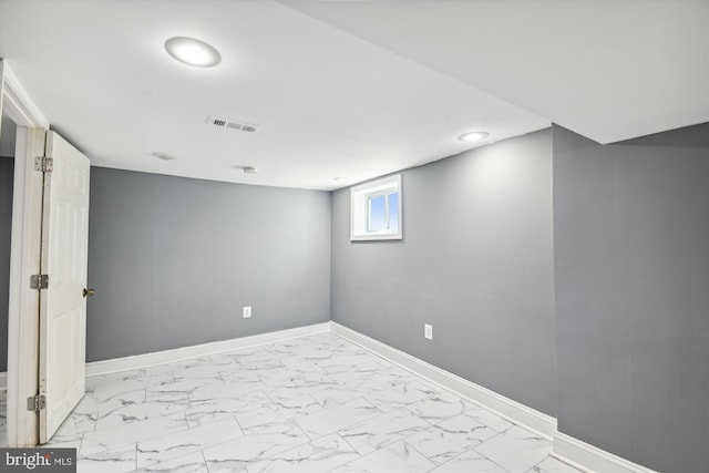 below grade area featuring marble finish floor, visible vents, and baseboards