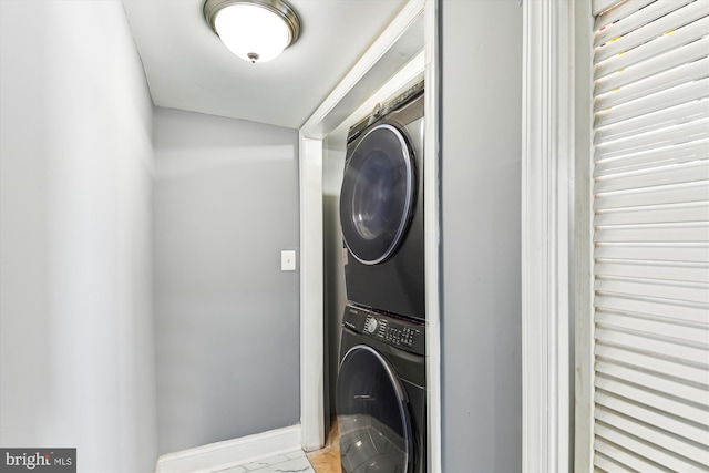 washroom with stacked washer and dryer and baseboards