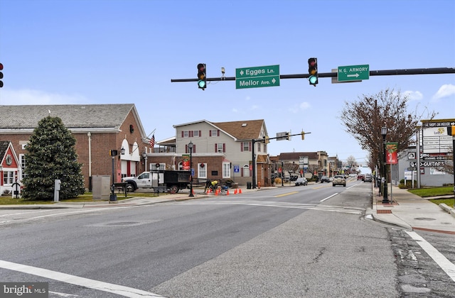 view of road featuring sidewalks, traffic lights, street lighting, and curbs