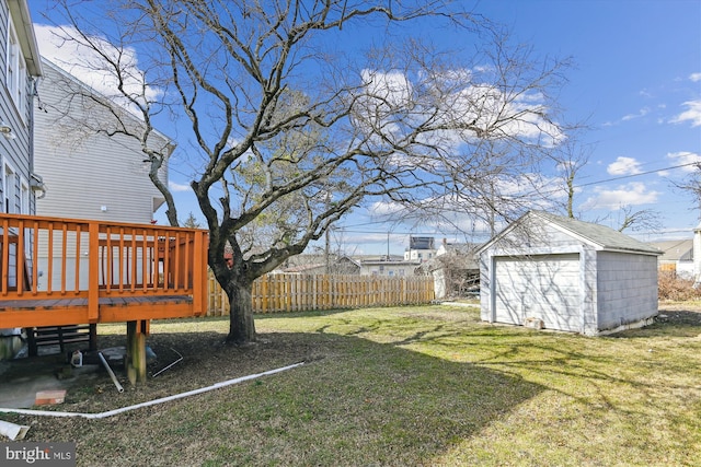 view of yard featuring a wooden deck, fence, and an outdoor structure