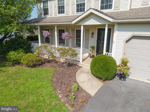 entrance to property with a garage, a yard, and a porch