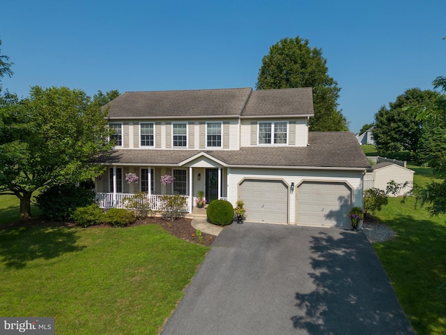 colonial home with covered porch, a garage, and a front lawn