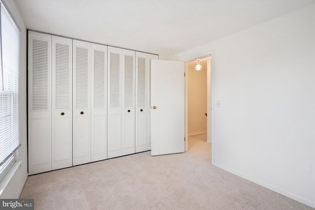 unfurnished bedroom featuring light colored carpet and a closet