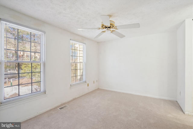 carpeted spare room featuring ceiling fan and a textured ceiling