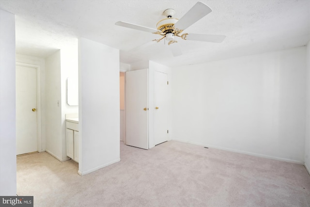 unfurnished bedroom with connected bathroom, light colored carpet, ceiling fan, a textured ceiling, and a closet