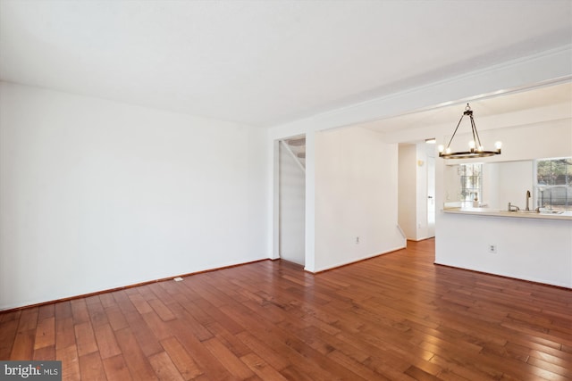 unfurnished living room featuring sink, hardwood / wood-style floors, and a notable chandelier