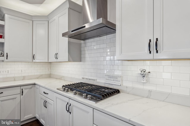 kitchen featuring white cabinetry, wall chimney exhaust hood, light stone countertops, decorative backsplash, and stainless steel gas stovetop