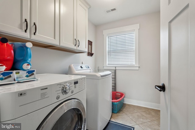 clothes washing area featuring light tile patterned flooring, cabinets, and separate washer and dryer