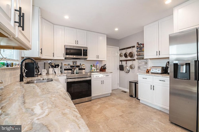 kitchen with appliances with stainless steel finishes, white cabinetry, and sink