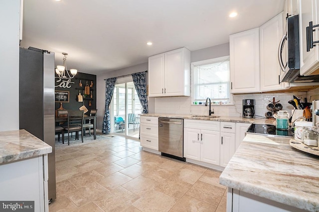 kitchen with pendant lighting, sink, white cabinets, and stainless steel appliances