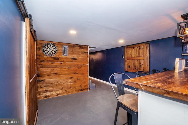 dining area featuring a barn door and wooden walls