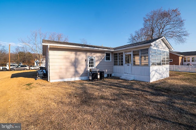 back of property with a yard and a sunroom