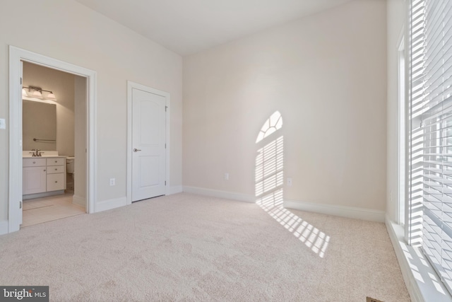 unfurnished bedroom with light carpet and ensuite bath