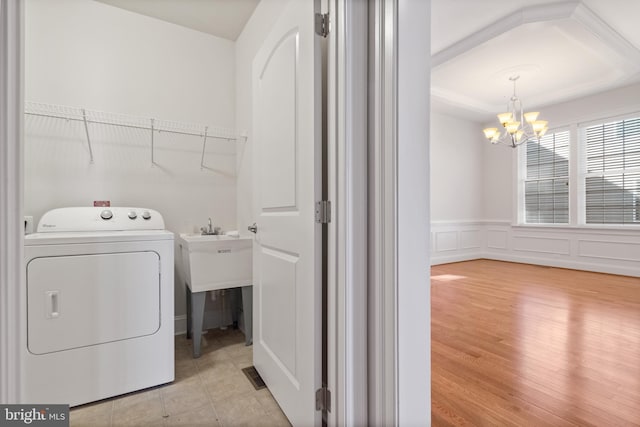 washroom with washer / dryer, an inviting chandelier, and light wood-type flooring