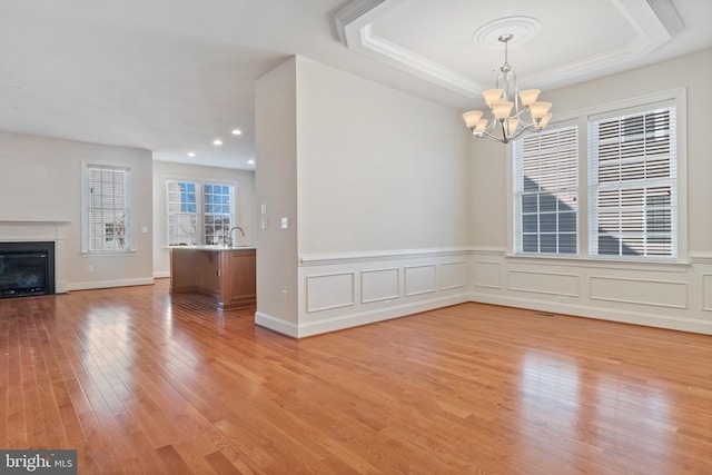 interior space with a raised ceiling, sink, a chandelier, and light hardwood / wood-style flooring