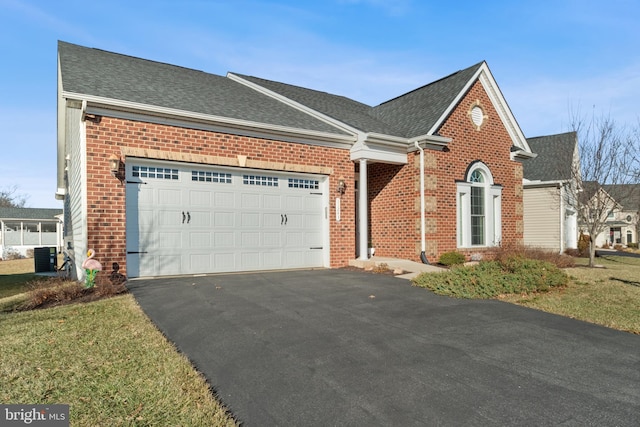 view of front of property with a garage, a front yard, and central air condition unit