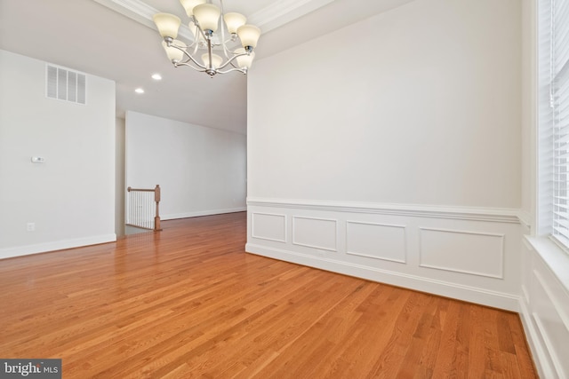 unfurnished room with an inviting chandelier and hardwood / wood-style flooring