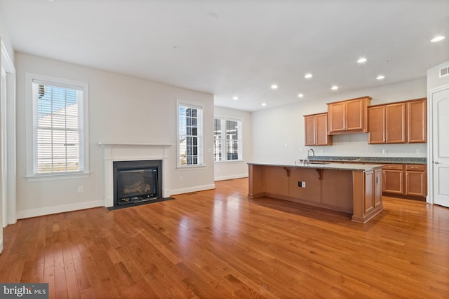 kitchen with sink, a breakfast bar, a center island with sink, and light hardwood / wood-style flooring