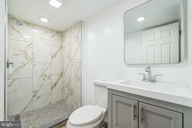 bathroom featuring toilet, vanity, and a tile shower