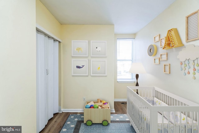 bedroom with dark hardwood / wood-style floors and a crib