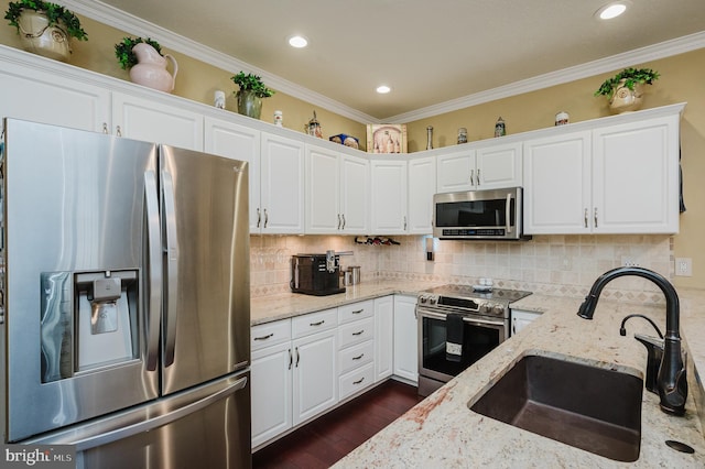 kitchen featuring appliances with stainless steel finishes, white cabinets, light stone countertops, and sink