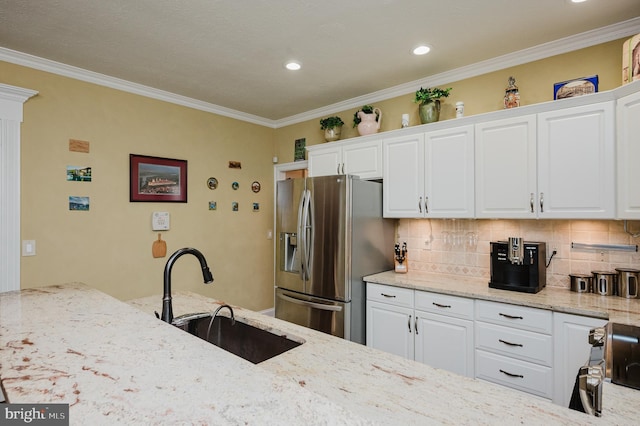 kitchen featuring sink, white cabinets, light stone counters, and stainless steel fridge