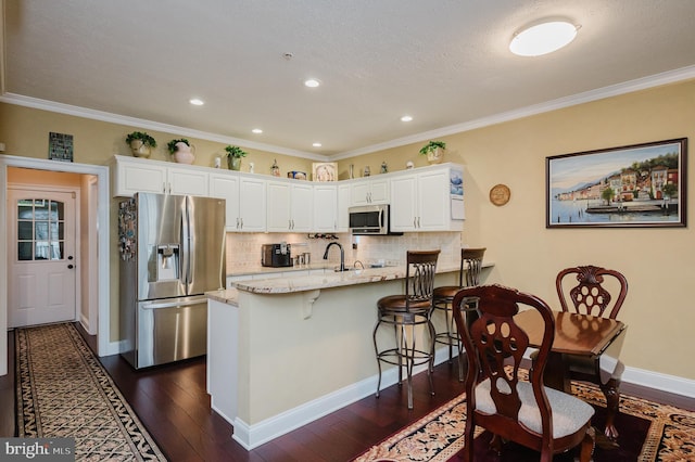 kitchen with light stone countertops, white cabinetry, ornamental molding, and appliances with stainless steel finishes