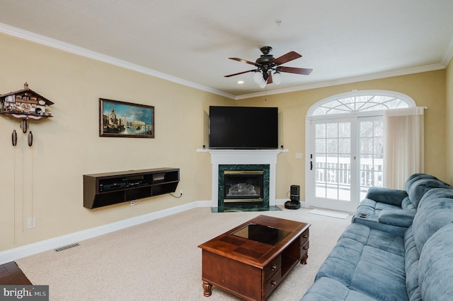 carpeted living room with ceiling fan, crown molding, and a high end fireplace